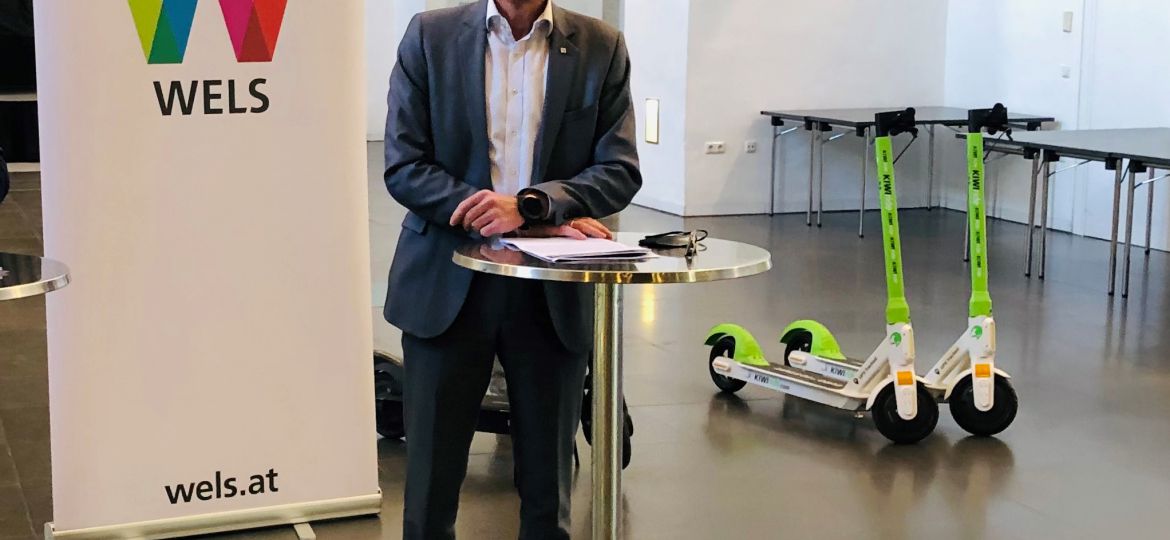 Gerhard Kroiß bei der Pressekonferenz. Er steht an einem Stehtisch. Im Hintergrund ein 