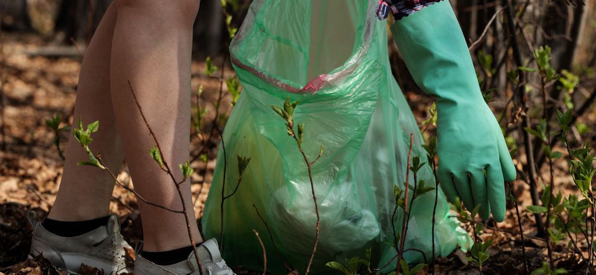 Eine Glasflasche wird von einer Person vom Boden aufgehoben