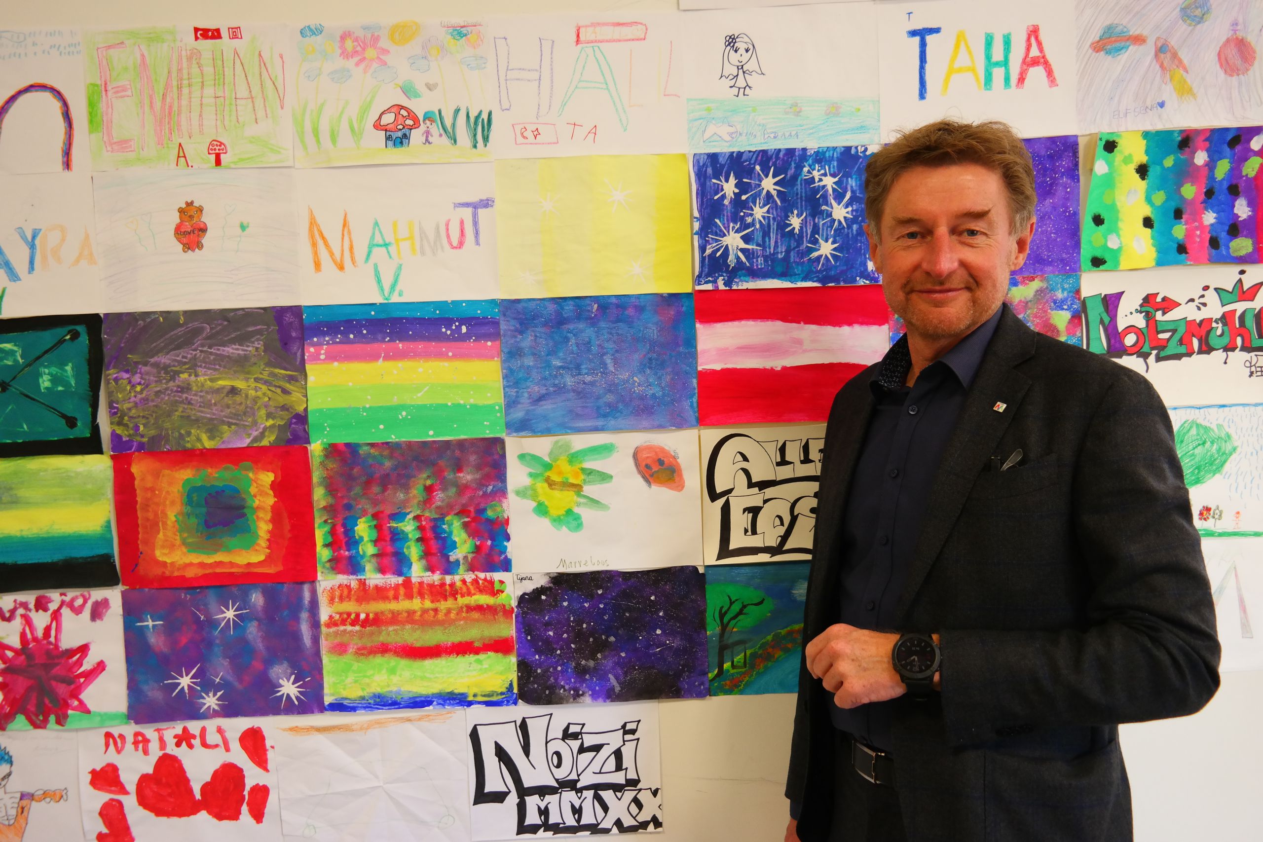 Gerhard Kroiß vor einer Wand voller Zeichnung von Jugendlichen die das Jugendtreff Noitzmühle ziehren