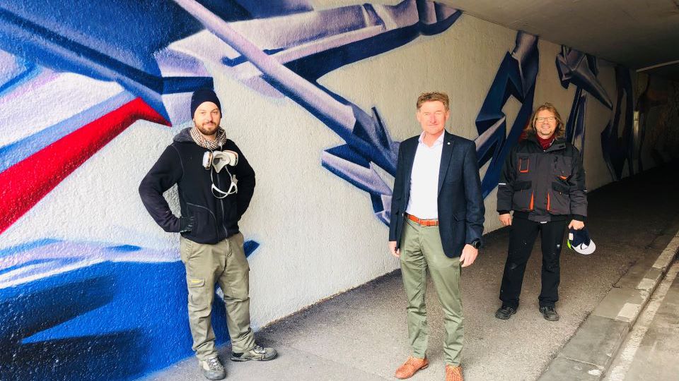 Gerhard Kroiß mit den beiden Künstlern vor der neuen Grafitti Wand der Unterführung Neustadt in Wels