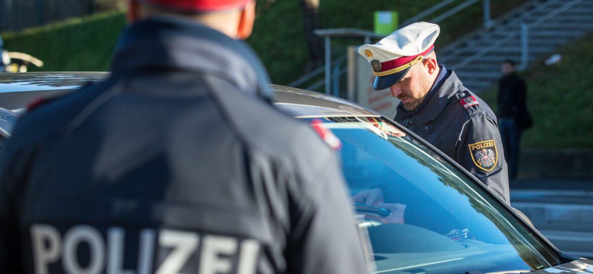 Polizist bei Kontrolle, schwarzes Auto