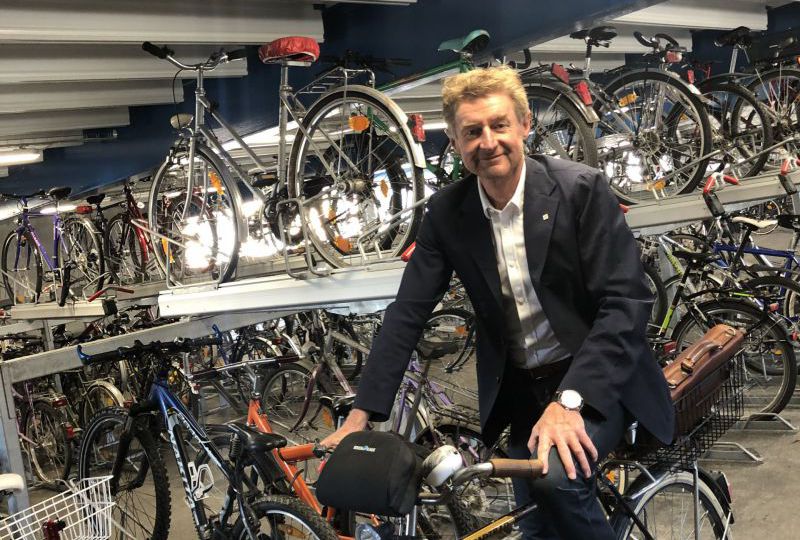 vzbgm. Gerhard Kroiß sitz auf seinem Fahrrad in der Fahrrad-Parkgarage am Welser ÖBB Parkdeck. Über ihm zu sehen ist die neue Videoüberwachung