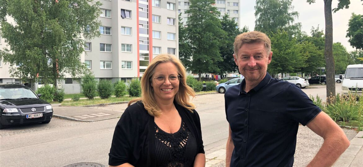 Vzbgm. Gerhard Kroiß und Vzbgm. Christa Raggl-Mühlberger stehen vor Hochhäusern in der Noitzmühle