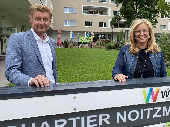 Herr Vizebürgermeister Kroiß und Frau Vizebürgermeister Raggl-Mühlberger stehen in der Noitzmühle hinter dem Schild 