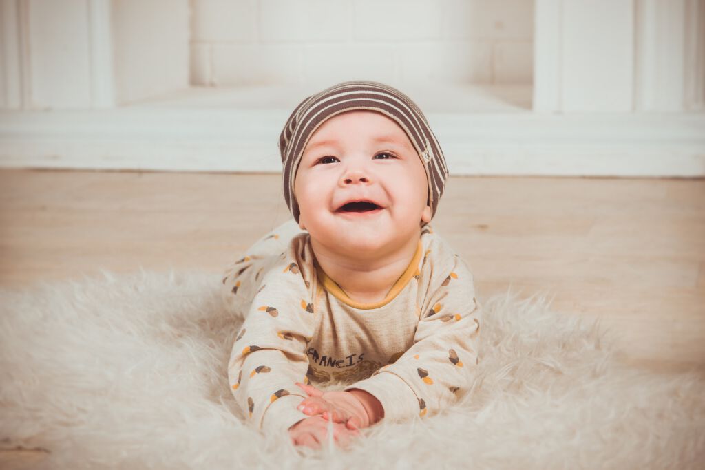 lachendes Baby liegt auf einem Fell am Boden