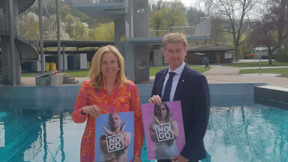Christa Raggl-Mühlberger + Gerhard Kroiß vor dem Sprungturm im Welldorado mit Plaketen der Kampagne 