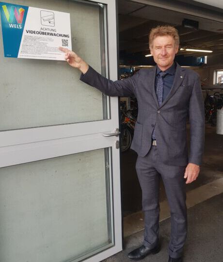 Vizebürgermeister Gerhard Kroiß vor dem Schild das auf die Videoüberwachung im Parkhaus hinweist