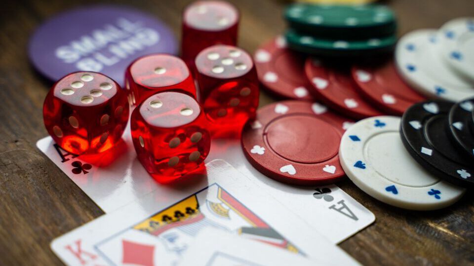 Spielkarten, Würfel und Jetons auf einem dunklen Holztisch