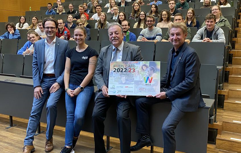 Herr Vizebürgermeister Gerhard Kroiß präsentiert gemeinsam mit der FH Wels die F(H)un Card im Hörsaal mit Studenten im Hintergrund